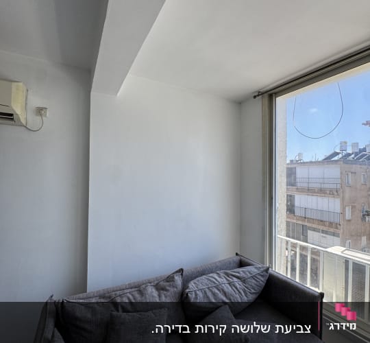 ספה אפורה ליד חלון עם נוף עירוני